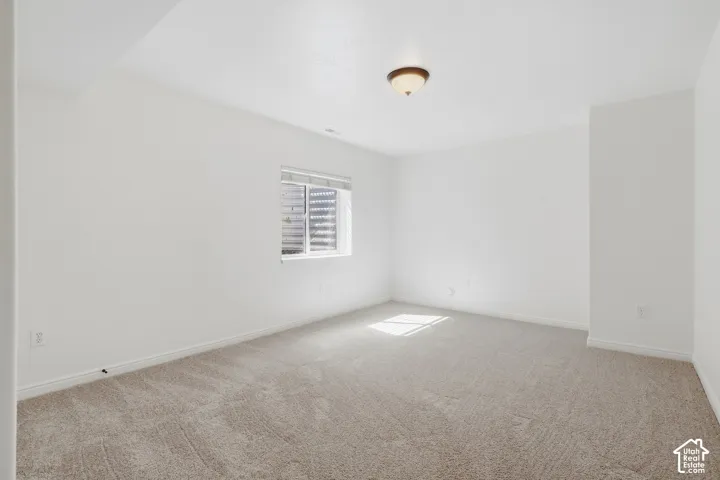 Recessed window with horizontal blinds, overhead flush mount light fixture, and neutral carpet flooring