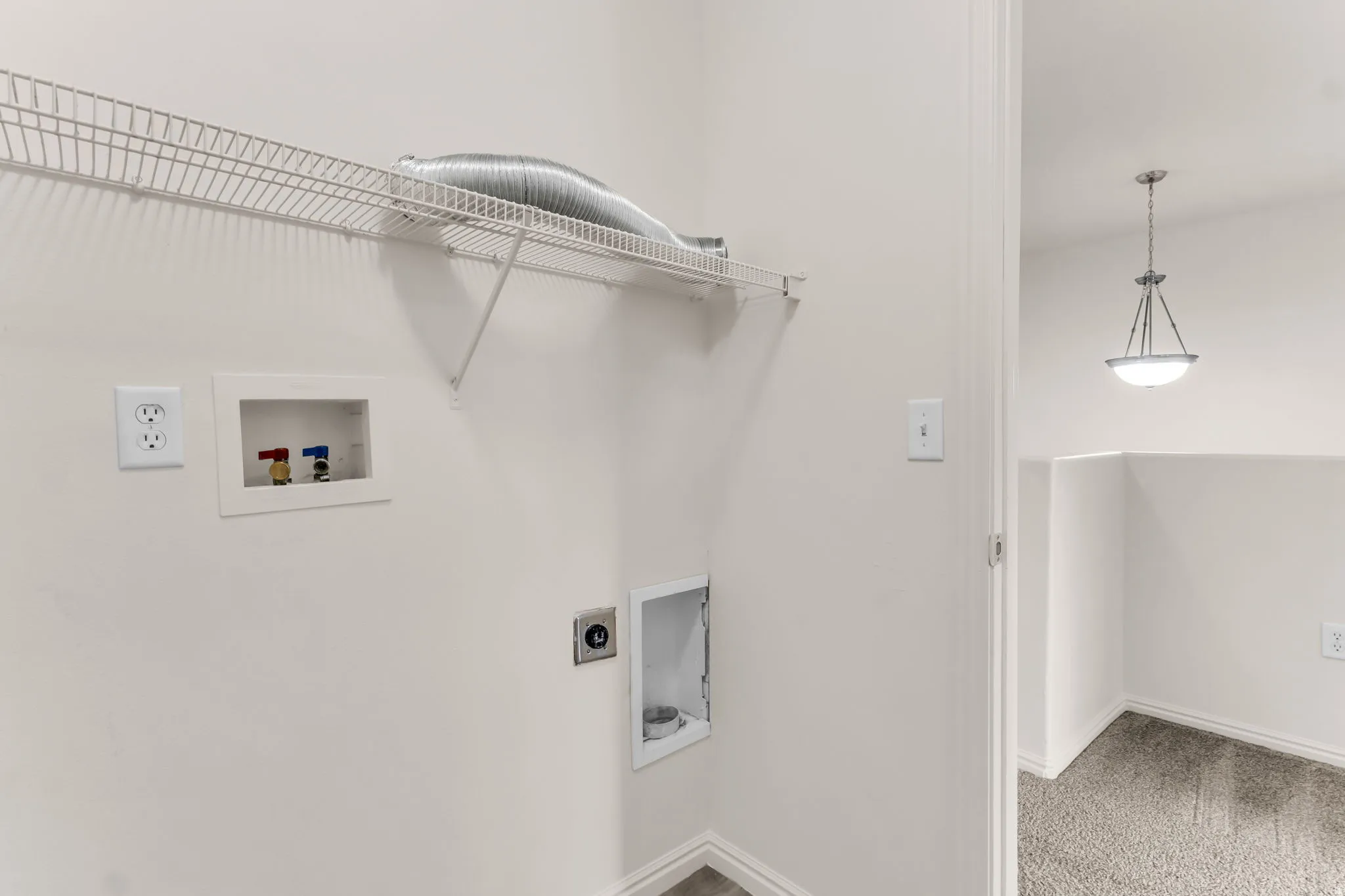 Laundry area with wire shelving, dryer vent, and utility hookups