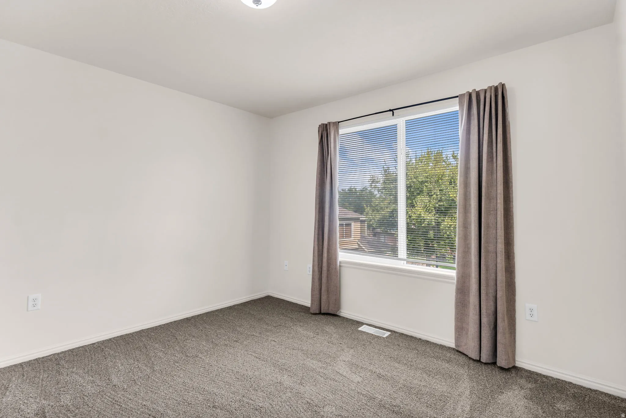 Neutral wall color, grey carpeting, and a window with blinds