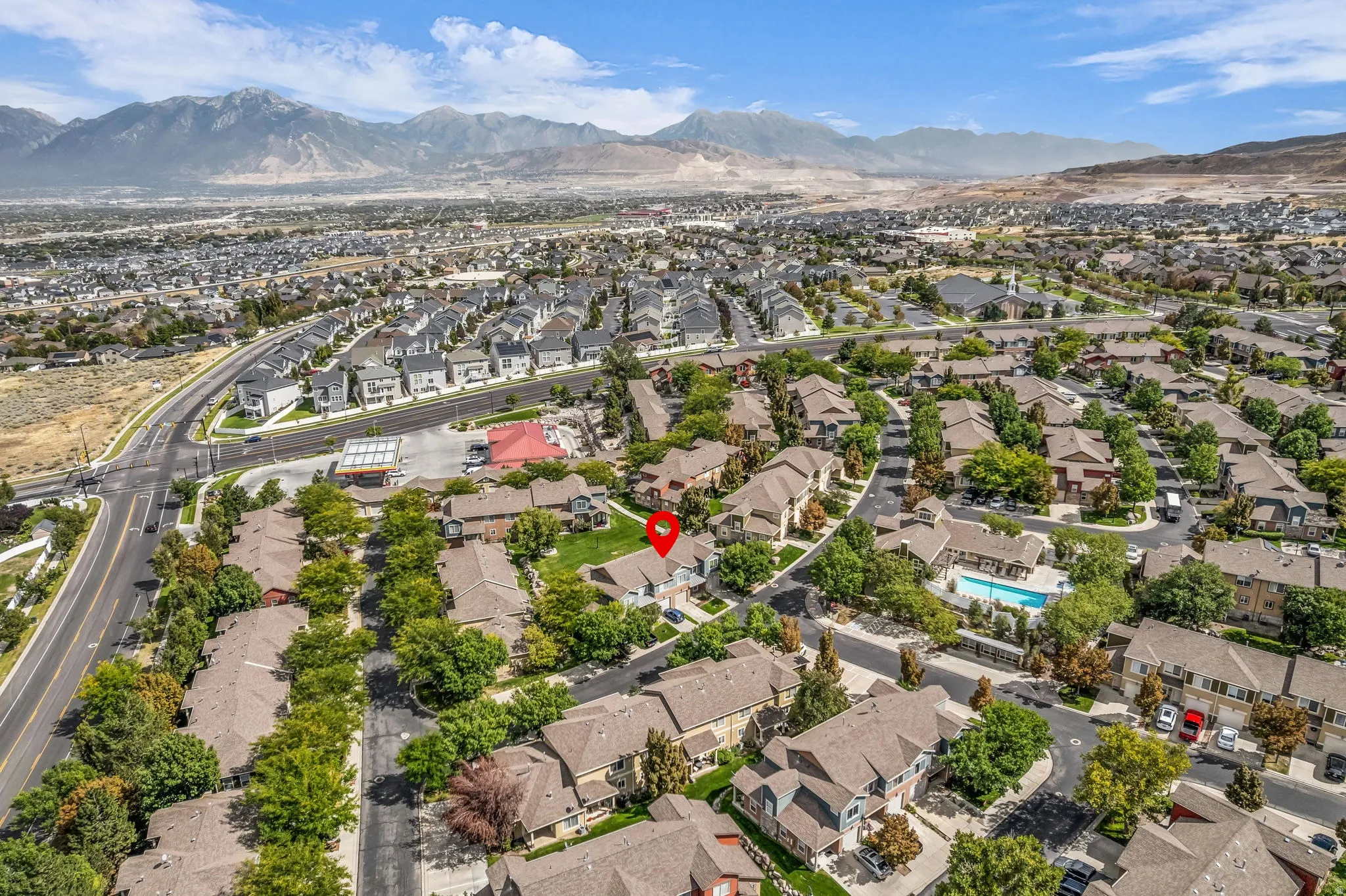 Mountainous backdrop, residential neighborhood setting, community pool, mature trees, and nearby commercial establishments