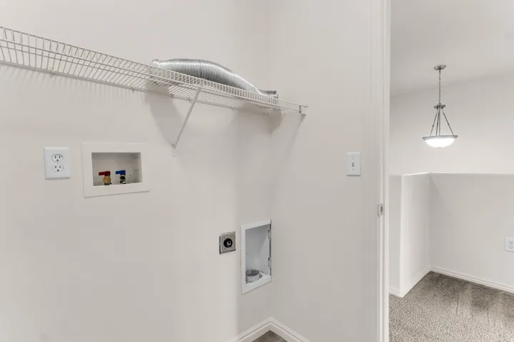 Laundry area with wire shelving, dryer vent, and utility hookups