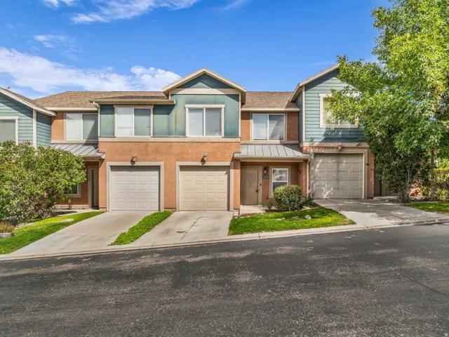 Two-story townhome with stucco and siding exterior, individual driveways, and integrated garages