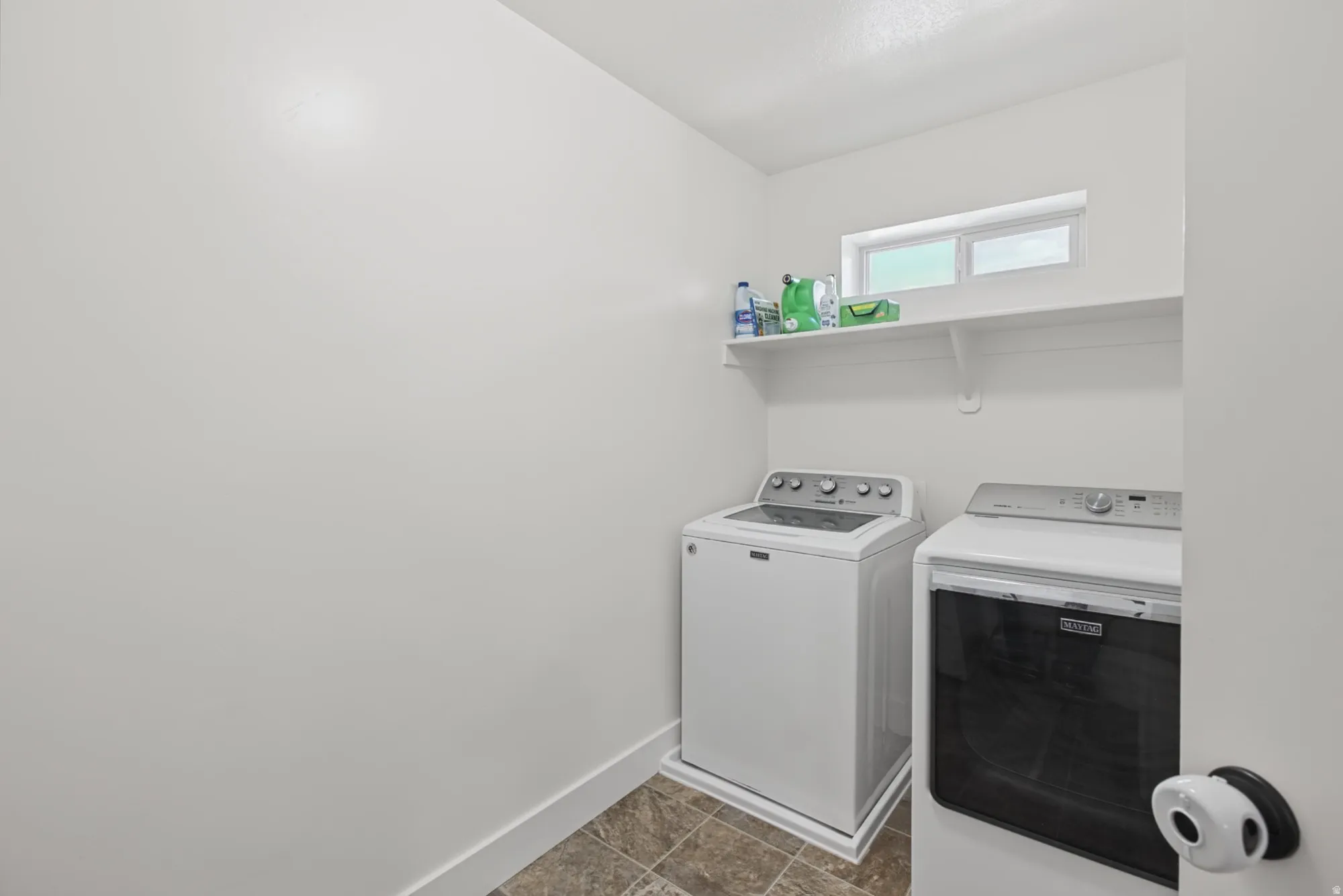 Laundry area featuring a window, wall-mounted shelving, and tile flooring