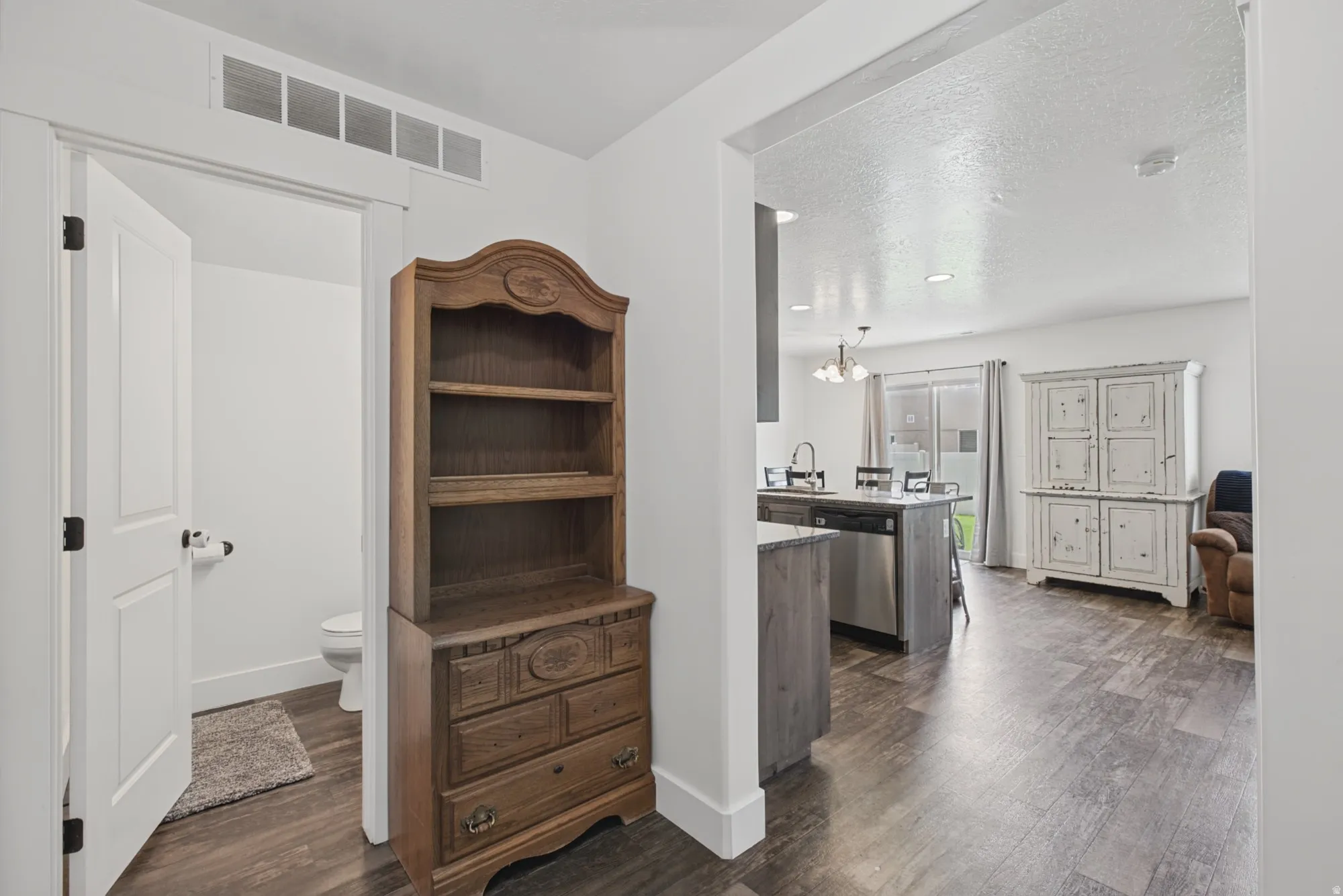 Open-concept living space with wood-finish flooring, kitchen island, stainless steel dishwasher, and recessed lighting