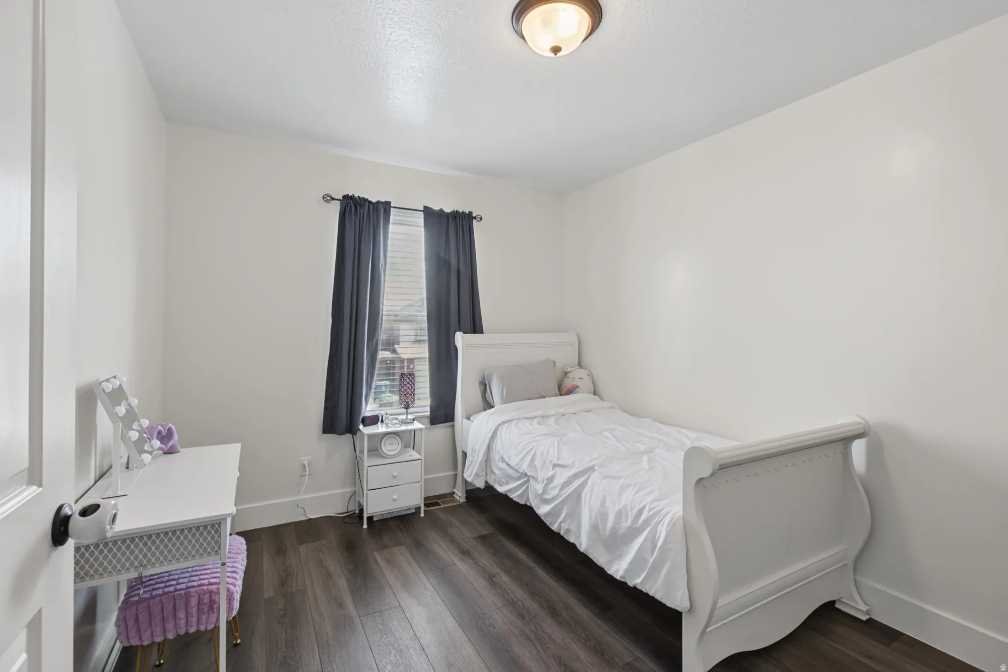 White walls, recessed window, dark wood-finish flooring, and a flush-mount ceiling light