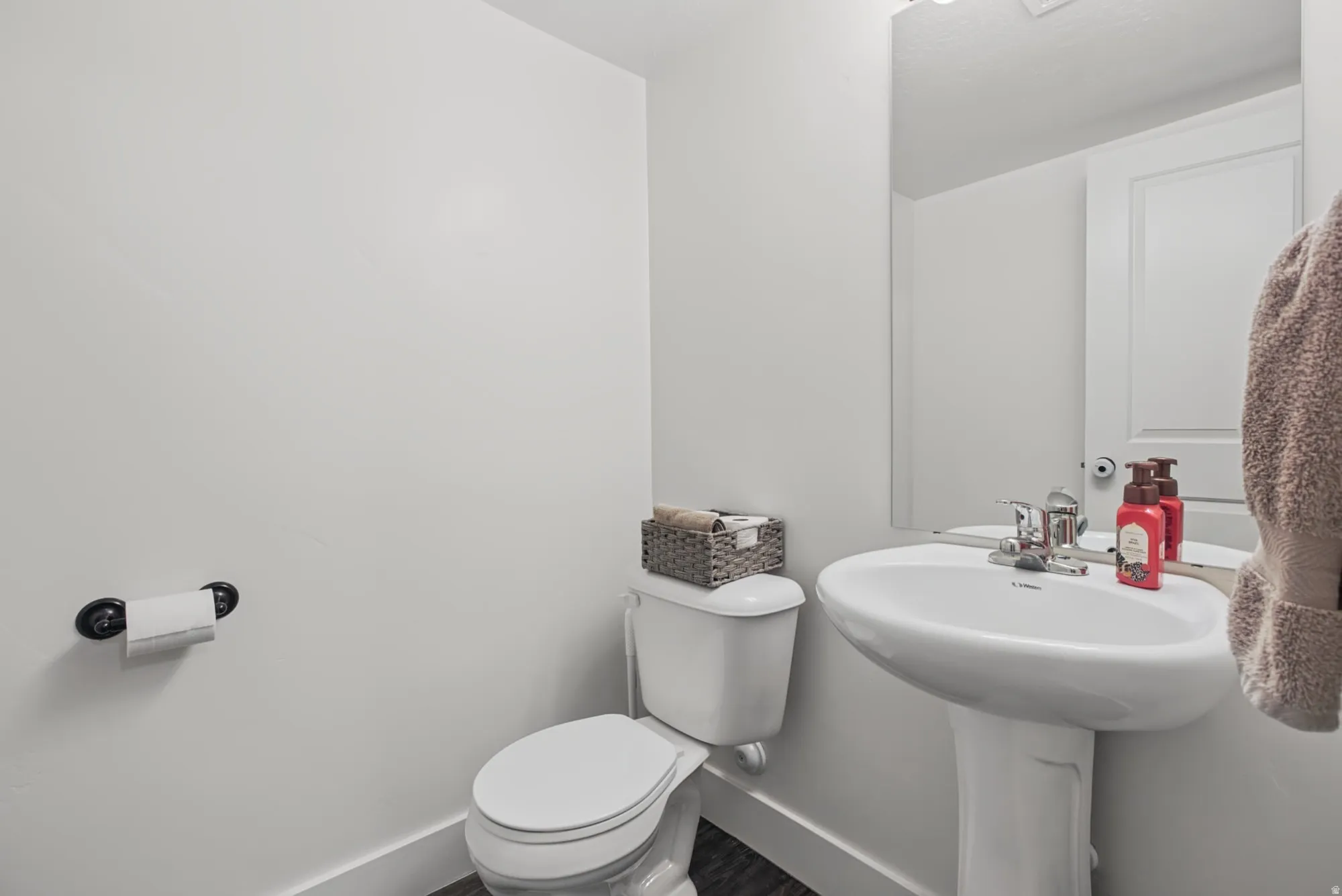 Pedestal sink with chrome faucet, toilet with matching white tank, and wall-mounted mirror