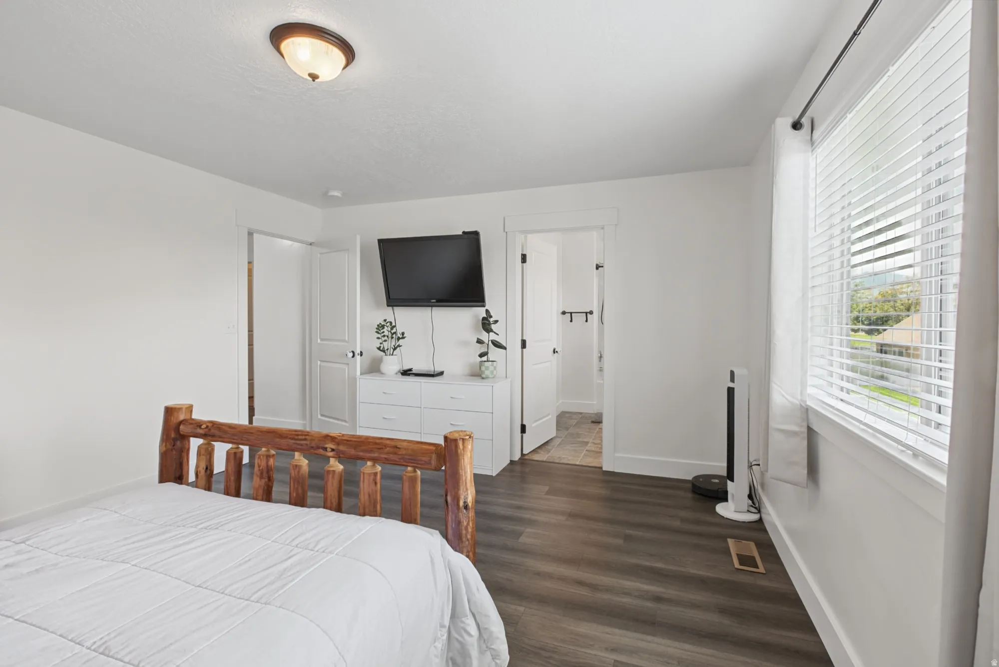 White walls, dark wood-finish flooring, white window blinds, and white trim