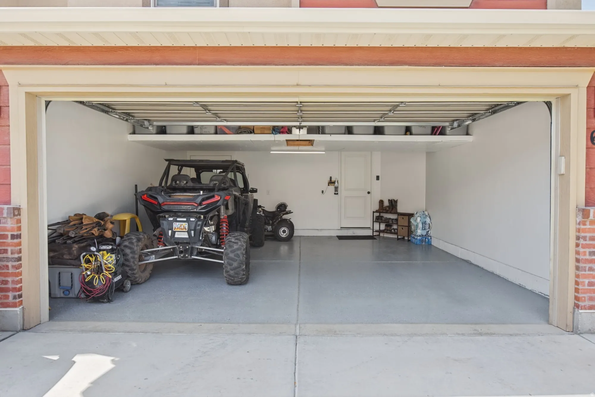 Garage featuring a painted concrete floor, white walls, and overhead storage shelving