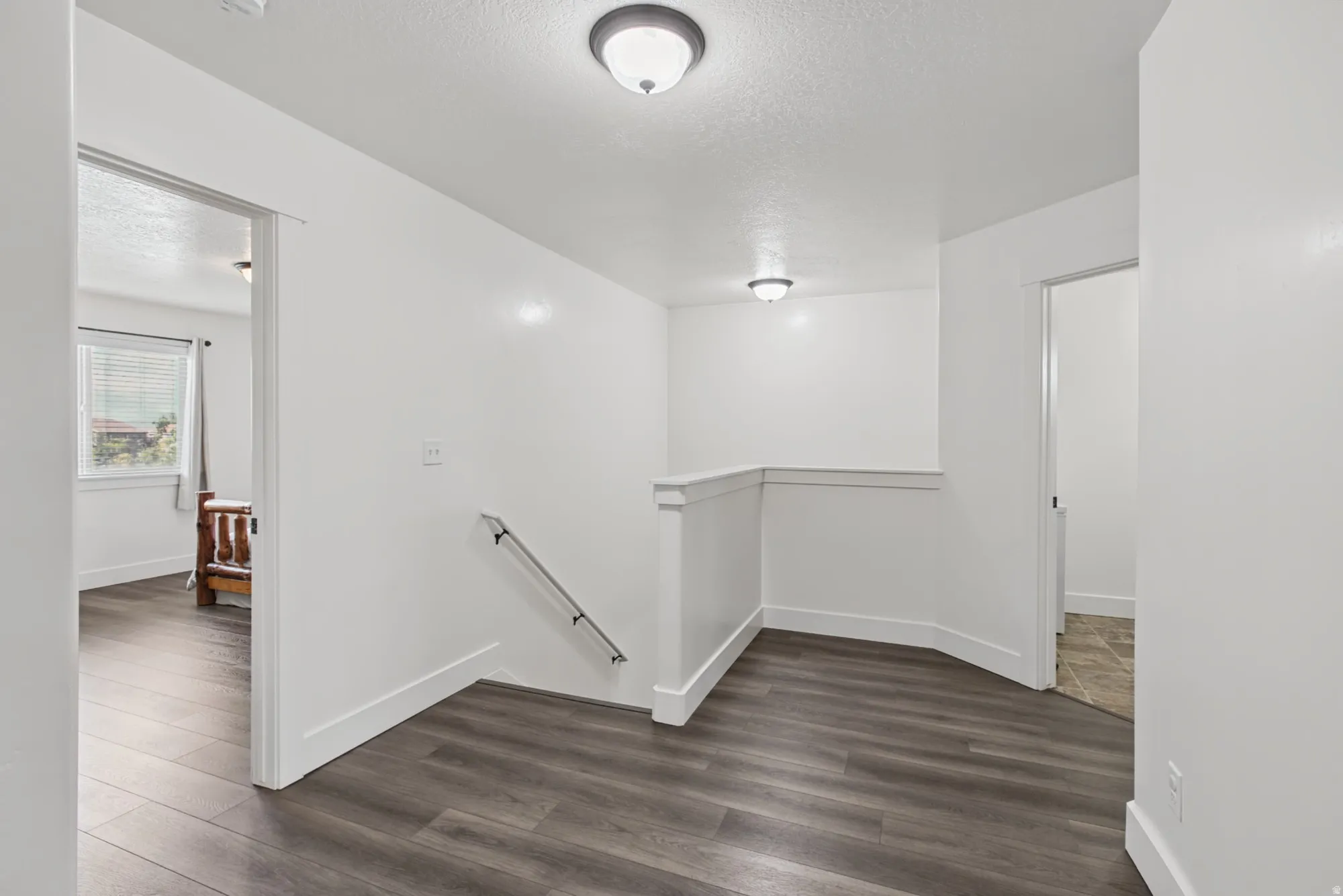 Wood-finish flooring, white walls, and contemporary flush-mount lighting