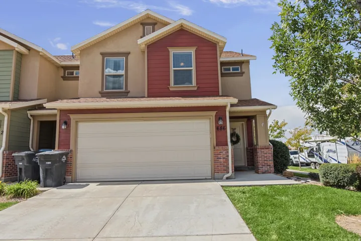 Two-story exterior with a red siding facade, brick accents, and a two-car garage