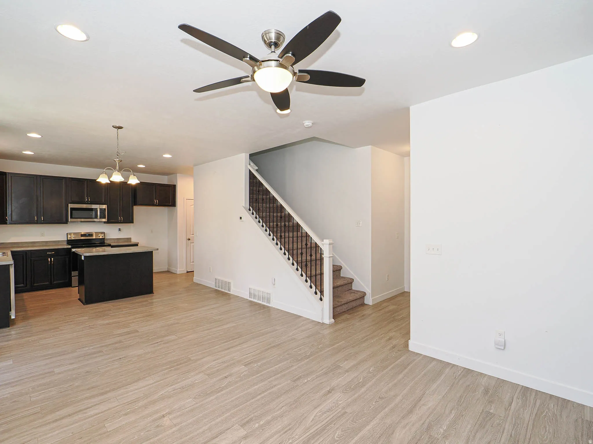 Wood-finish flooring throughout, recessed ceiling lighting, and a ceiling fan with integrated lighting