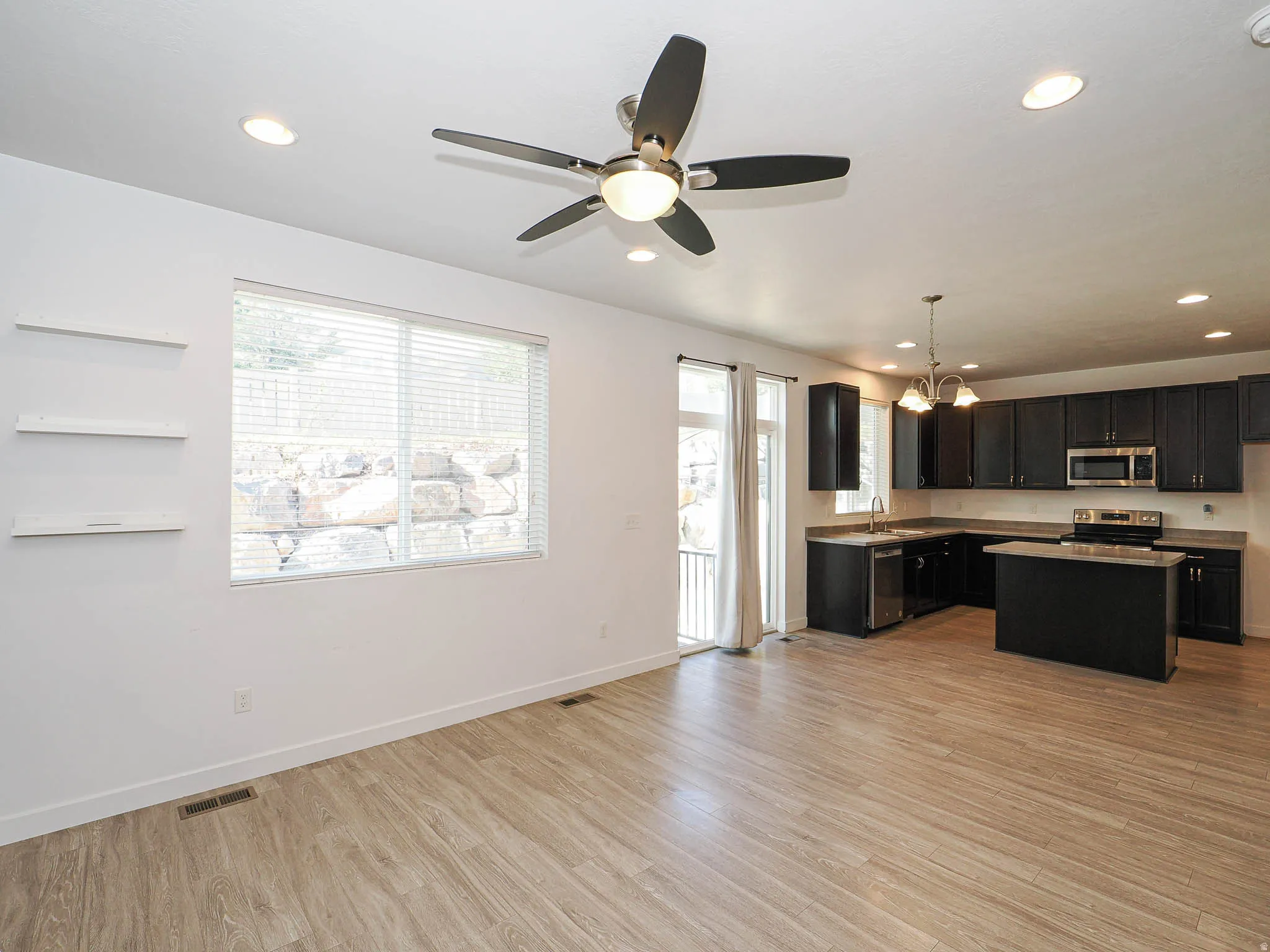 Open-concept living space featuring wood-finish flooring, recessed lighting, and a ceiling fan
