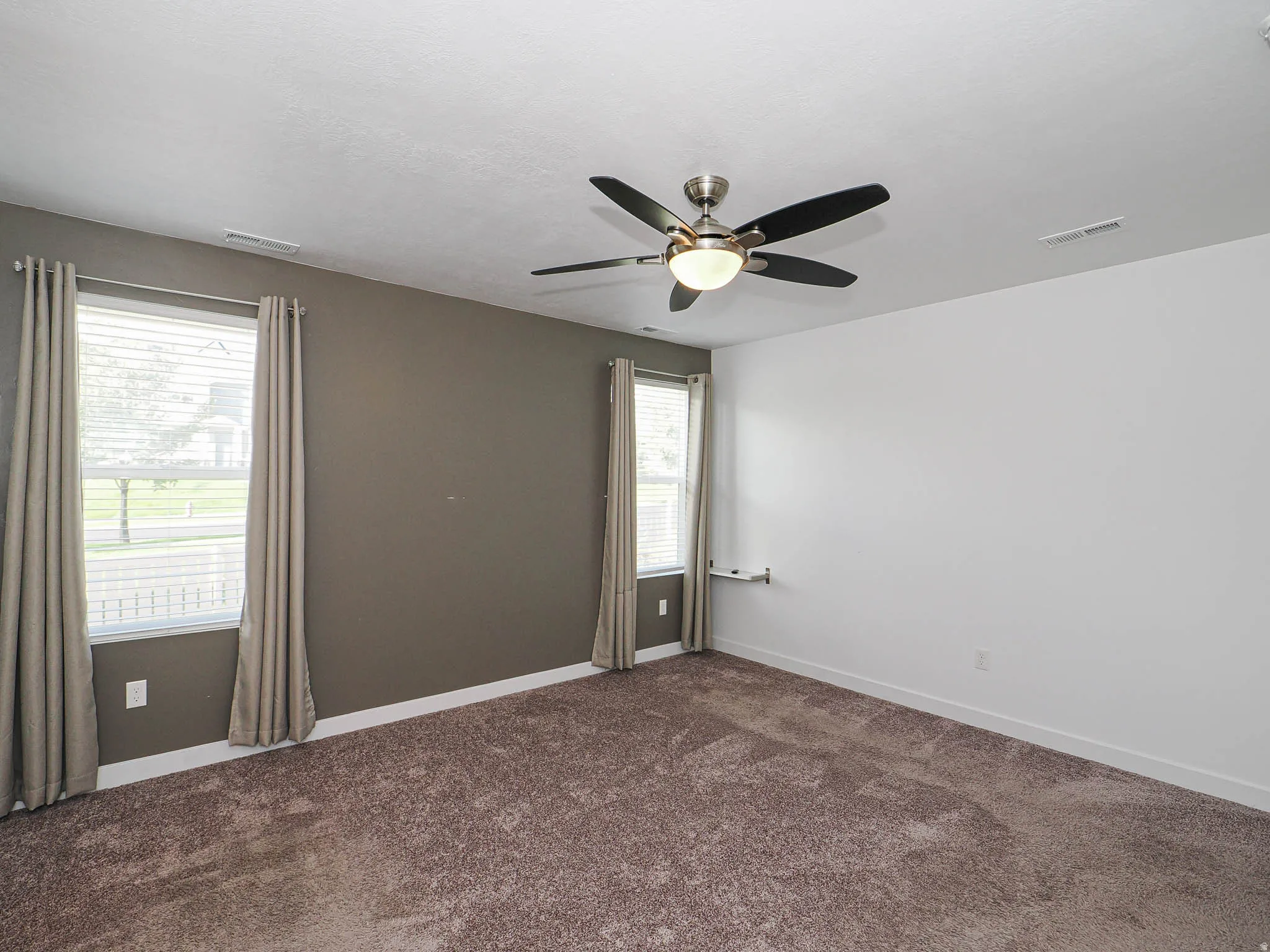 Ceiling fan with integrated lighting, textured carpeting, multiple windows with blinds, and contrasting wall colors
