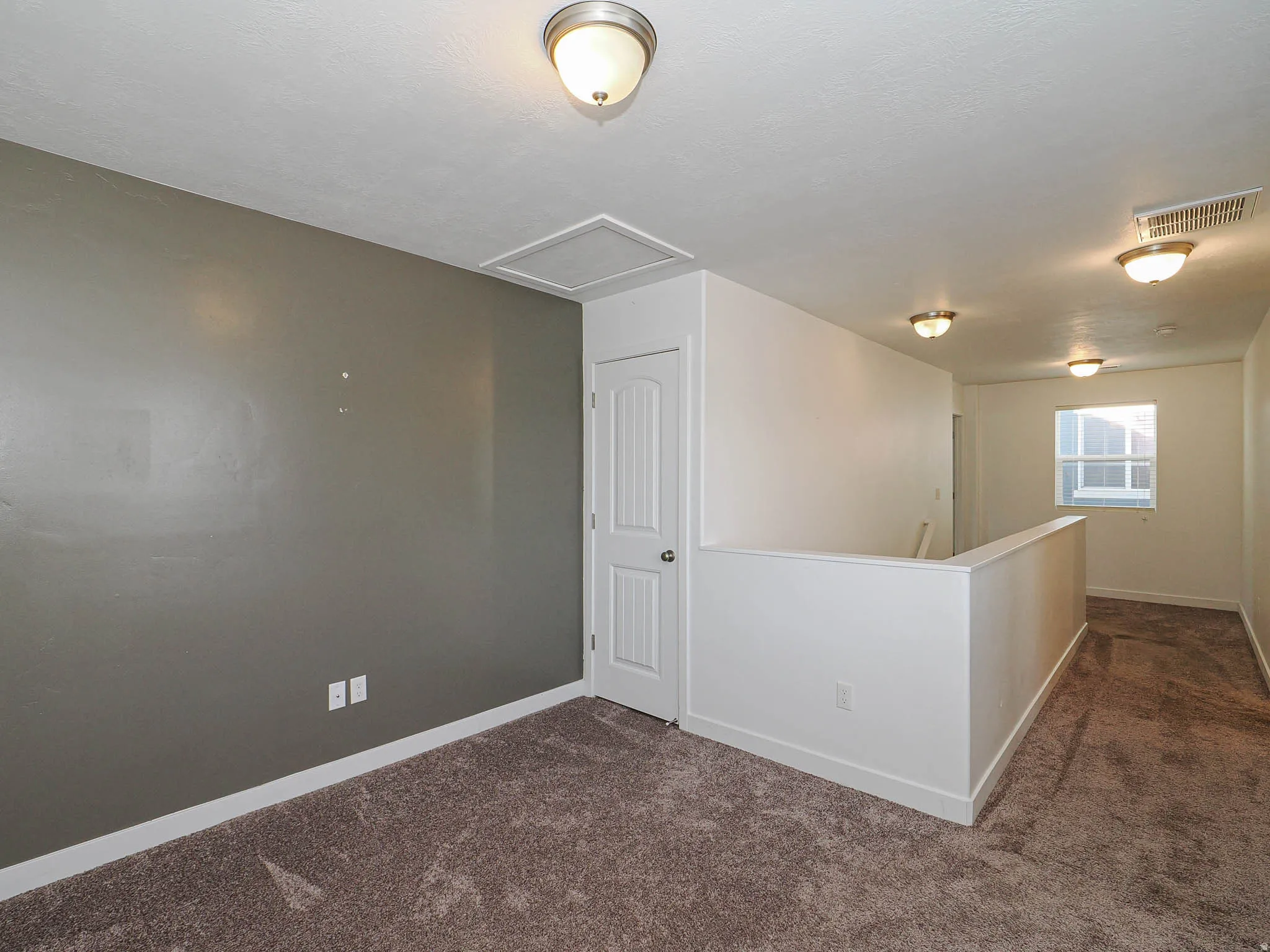 Carpeted flooring, overhead lighting, interior window, and a white interior door with hardware