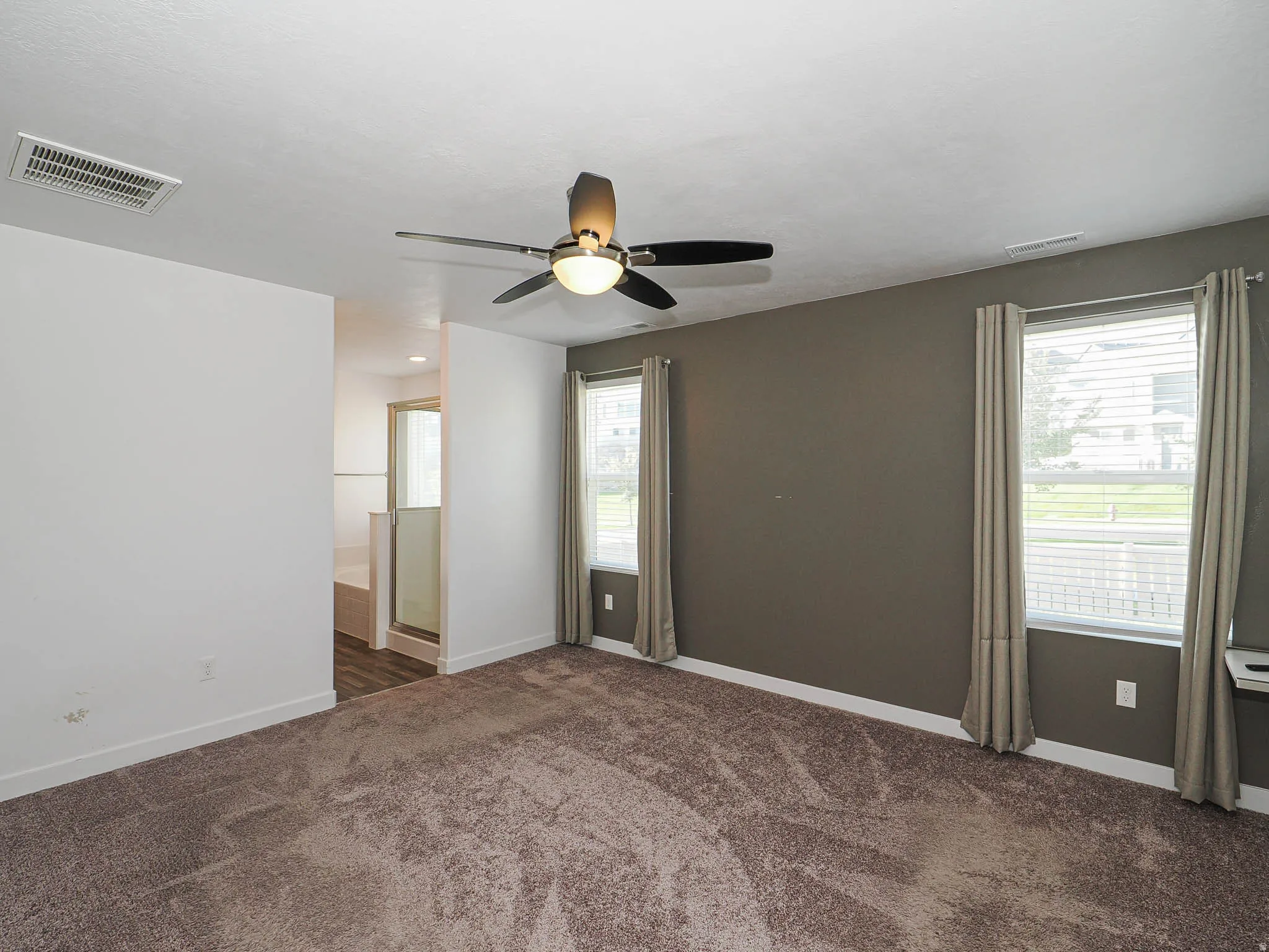 Recessed lighting, ceiling fan, two large windows with blinds, built-in shelving, and carpeting