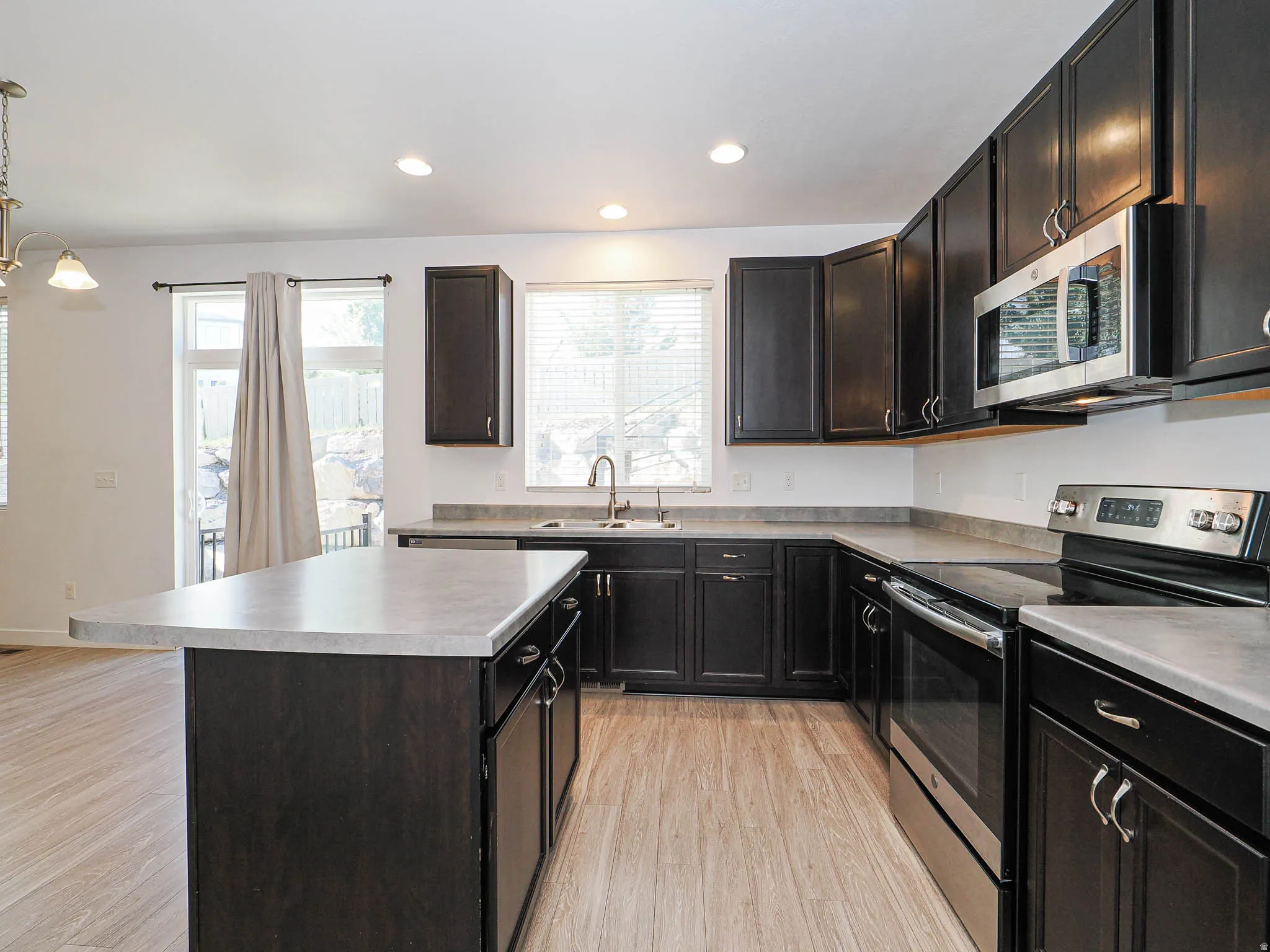 Kitchen featuring dark wood-finish cabinetry, stainless steel appliances, a center island, and wood-finish flooring