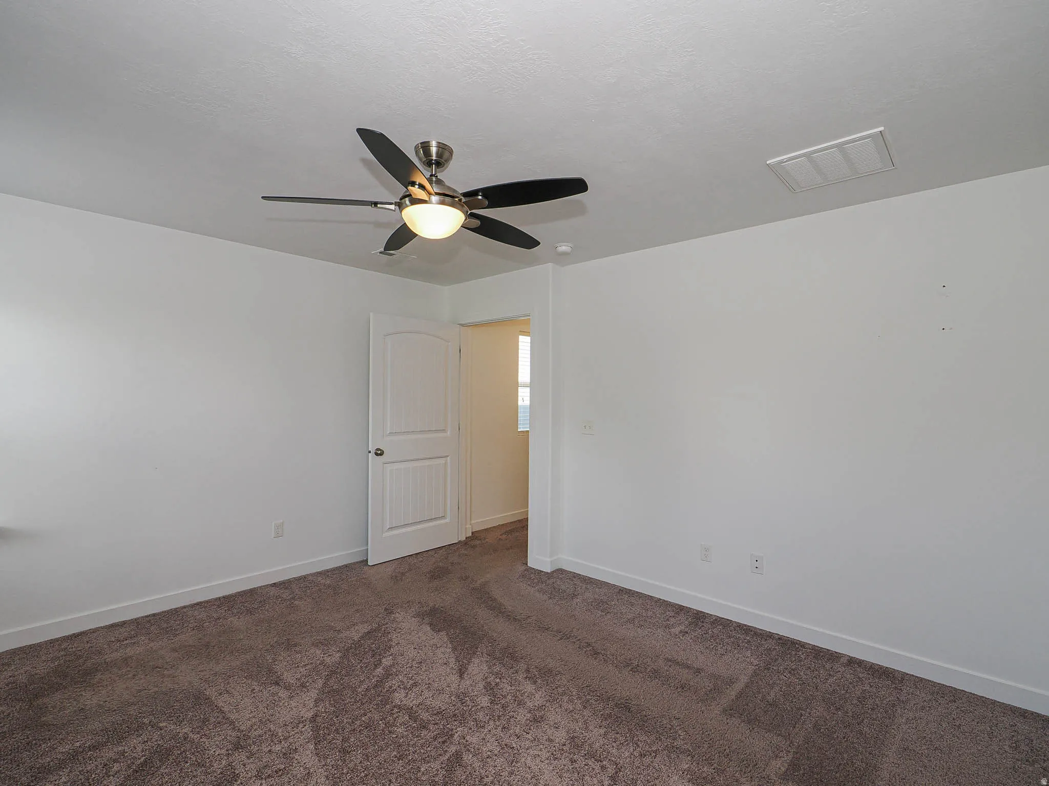 Neutral wall paint, ceiling fan with integrated lighting, textured carpet flooring, and white trim