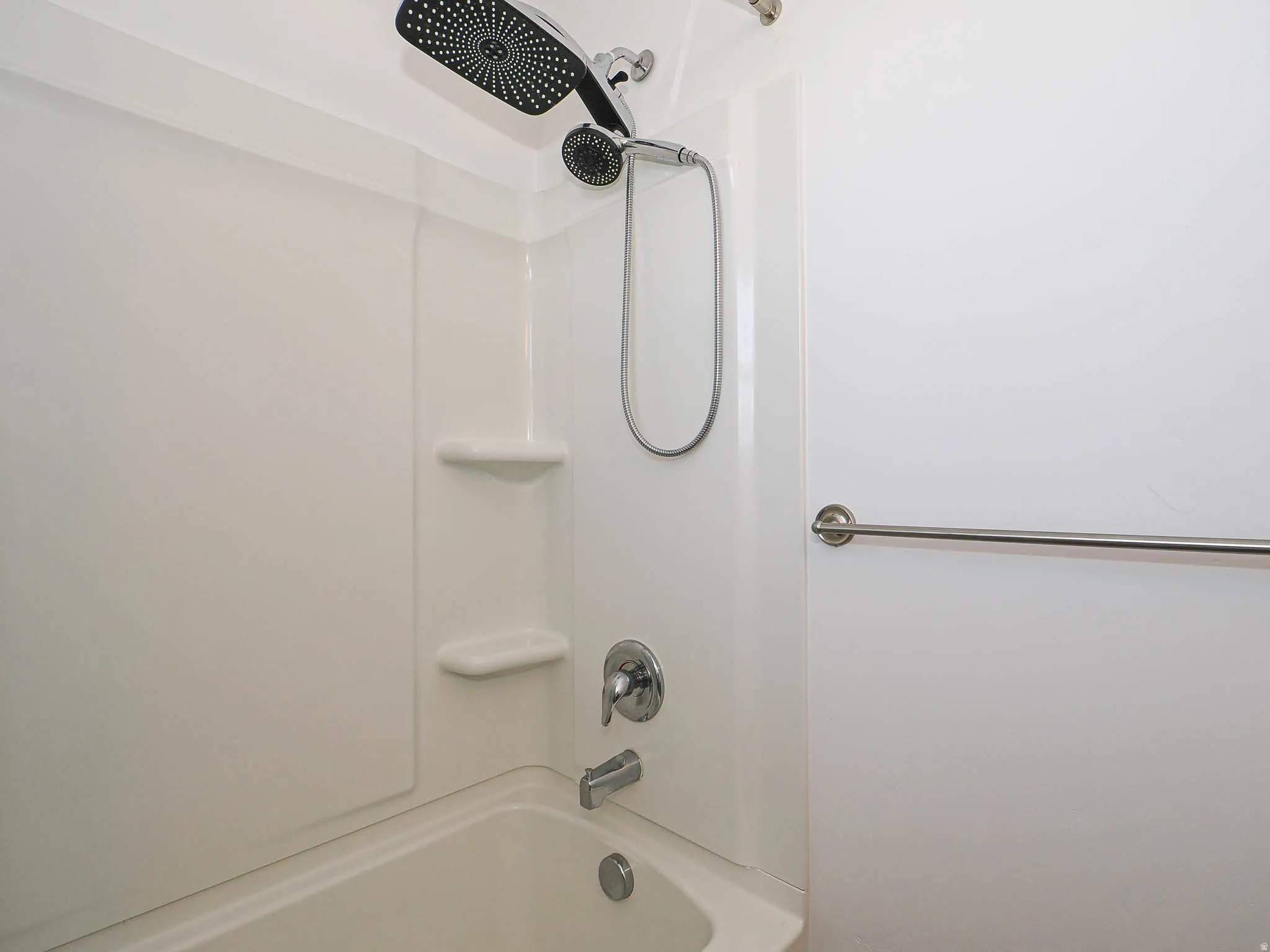 Bathtub with integrated shower, dual shower heads, and built-in shelving
