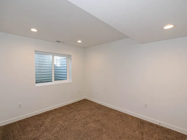 Recessed ceiling lighting, white walls, white trim, brown carpet, and a white-framed window