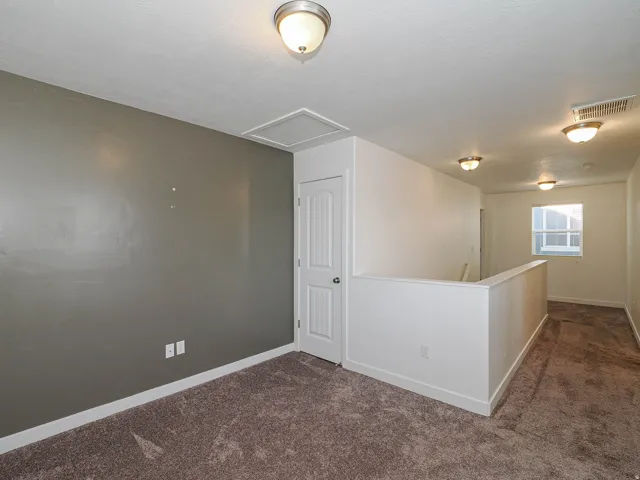 Carpeted flooring, overhead lighting, interior window, and a white interior door with hardware