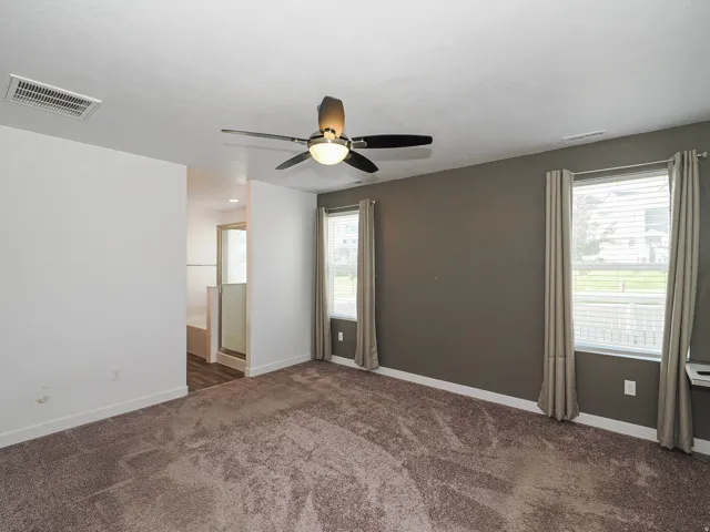 Recessed lighting, ceiling fan, two large windows with blinds, built-in shelving, and carpeting