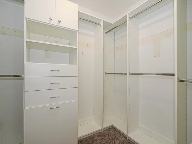 Built-in white cabinetry with chrome hardware, integrated shelving, and multiple hanging rods