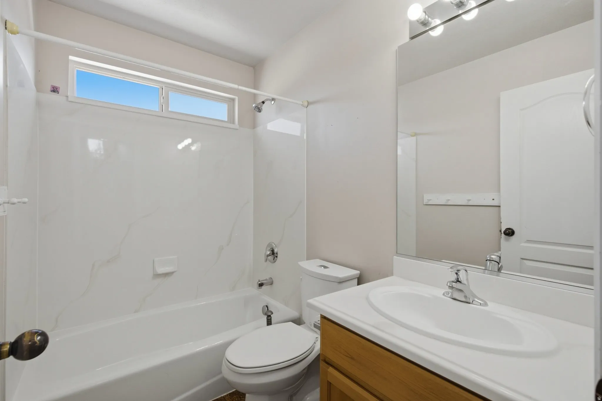 Tub/shower combination with white patterned surround and an overhead window