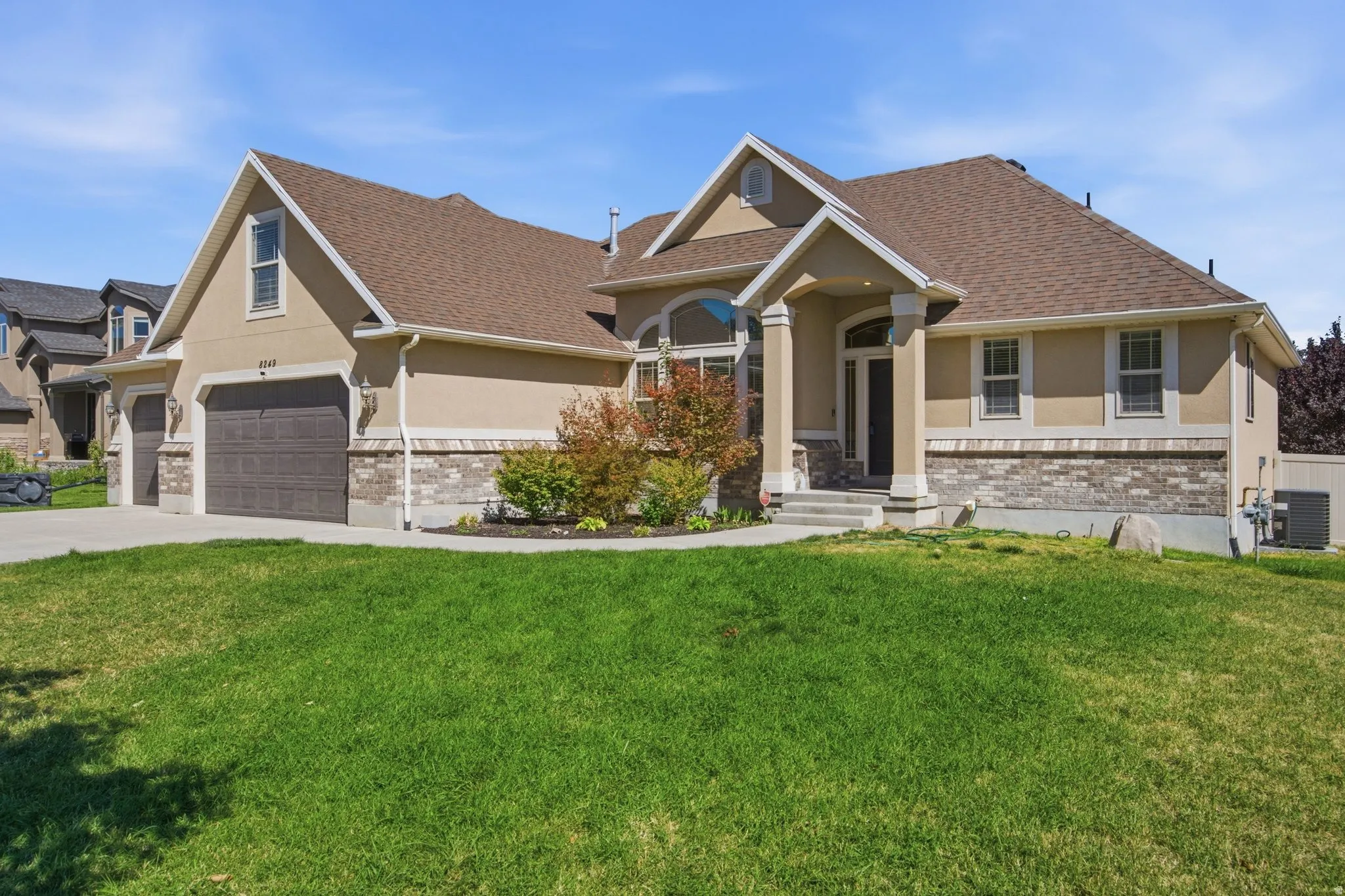 Exterior featuring stucco siding, stone accents, multiple gables, an arched entry, and an attached two-car garage