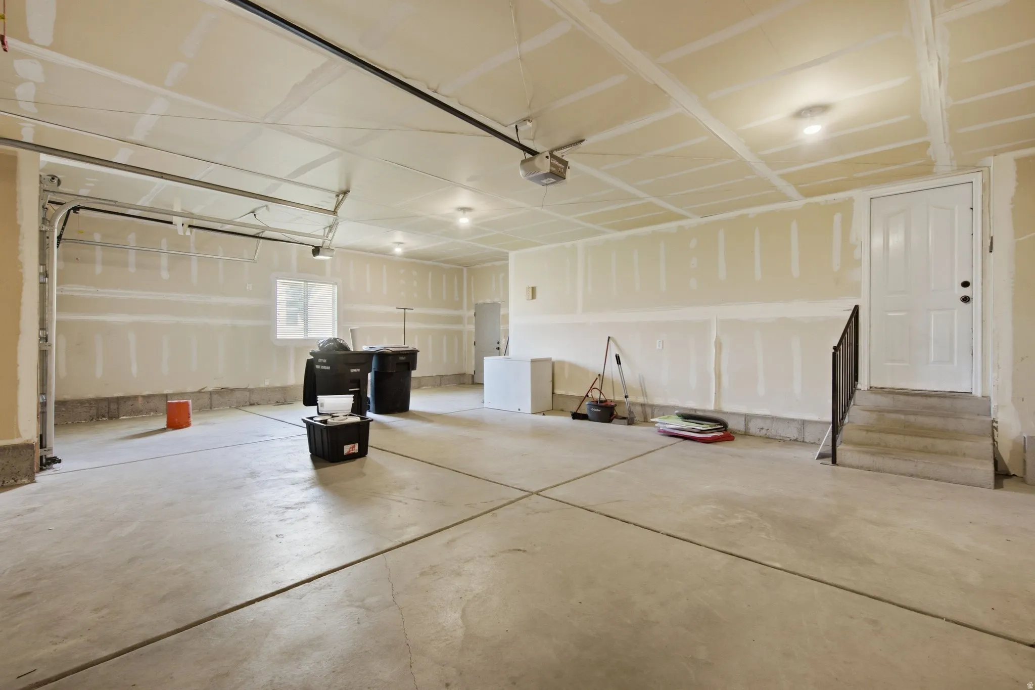 Spacious garage featuring a concrete floor, built-in window, and direct access door