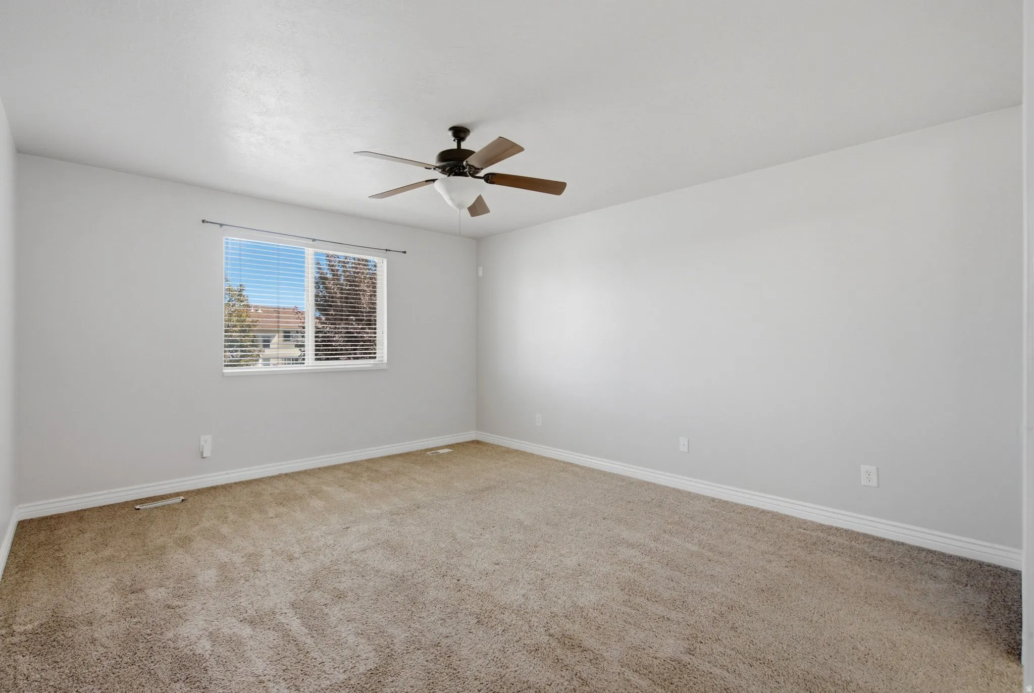 Neutral wall paint, ceiling fan with light fixture, carpeted flooring, and a window with blinds