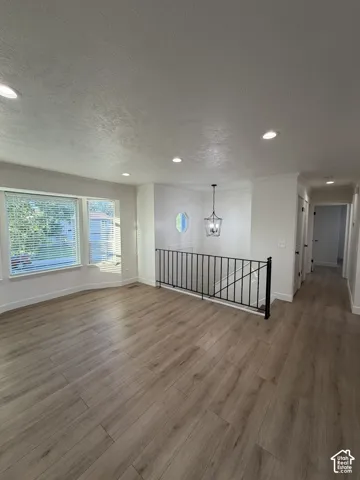 Wood-finish flooring, recessed lighting, multi-pane bay window, decorative octagonal accent window, and metal stair railing with pendant lantern fixture