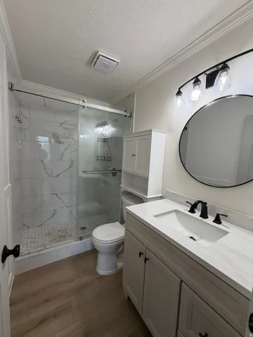 Walk-in shower with sliding glass doors, white tiled walls, and hexagonal floor tile