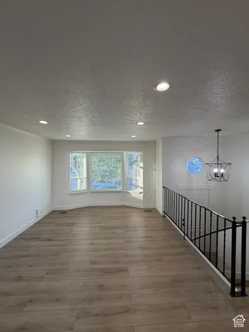 Recessed lighting, wood-finish flooring, bay window, wrought iron railing, and a decorative circular window
