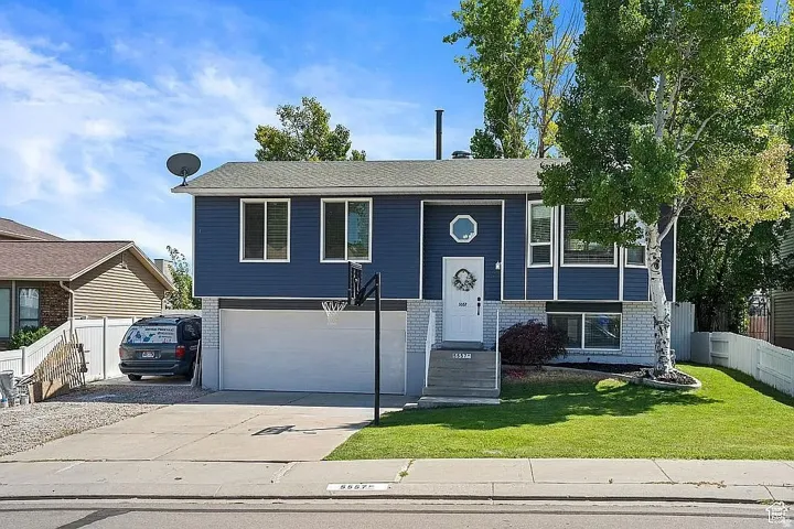 Split-level residence featuring blue siding, a two-car garage, and a concrete driveway