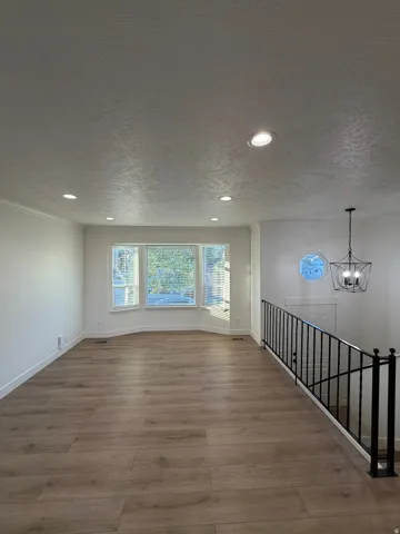 Recessed lighting, wood-finish flooring, bay window, wrought iron railing, and a decorative circular window