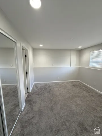 Interior space featuring neutral-toned carpeting, recessed ceiling lighting, two-tone wall paint with a chair rail, and mirrored closet doors