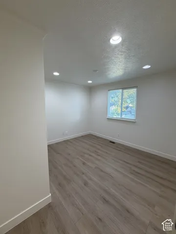 Neutral-toned interior room featuring wood-finish flooring, recessed lighting, and a single-pane sliding window