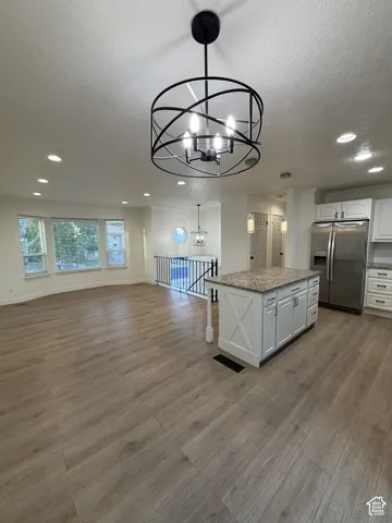 Wood-finish flooring, recessed lighting, bay window, kitchen island with granite-style countertop, and stainless steel appliances