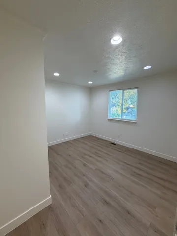 Recessed lighting, crown molding, wood-finish flooring, and a window with a white frame