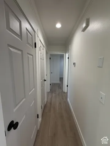 Hallway featuring wood-finish flooring, recessed lighting, and crisp white panel doors with matte black hardware