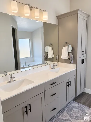 Dual vanity with integrated sinks, white countertops, gray cabinetry, and matte black hardware