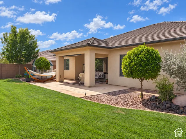 Expansive backyard featuring a manicured lawn, a covered patio, and a dedicated rock garden