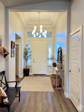 Entryway featuring wood-finish flooring, a coffered ceiling, and a contemporary chandelier