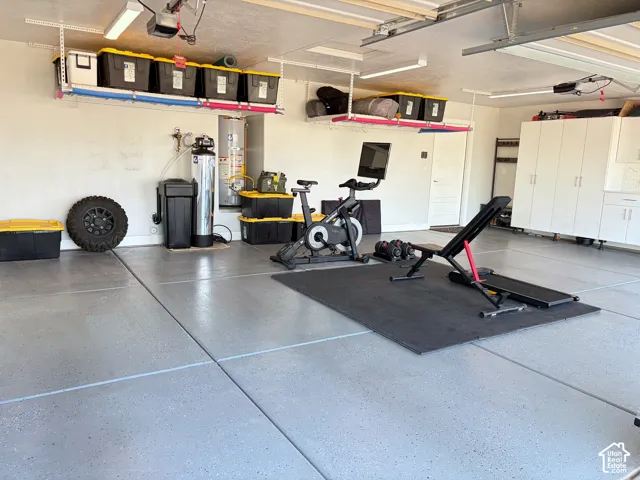 Spacious garage featuring a durable epoxy floor coating, extensive overhead storage racks, and built-in white cabinetry