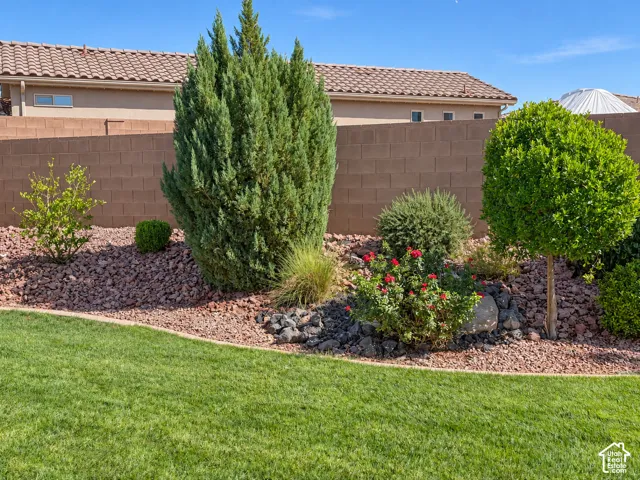 Expansive lawn bordered by a sculpted landscape bed featuring mature shrubs, flowering plants, and decorative rock elements