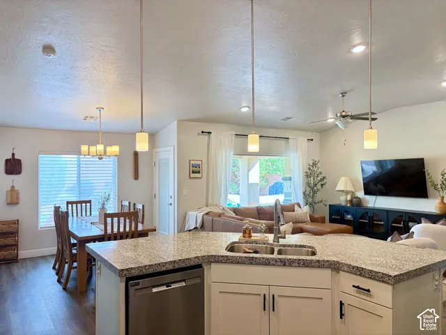 Open-concept living space featuring a kitchen island with stone-finish countertop, wood-finish flooring, and recessed lighting