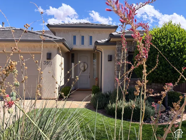 Stucco exterior with stone accents, a tiled roof, and a prominent front entry with a transom window and recessed lighting