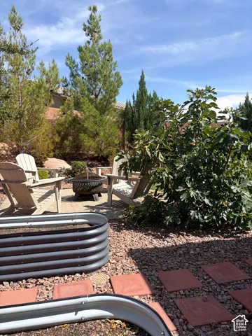 Landscaped outdoor area featuring a fire pit, paver patio, stone ground cover, and raised garden beds