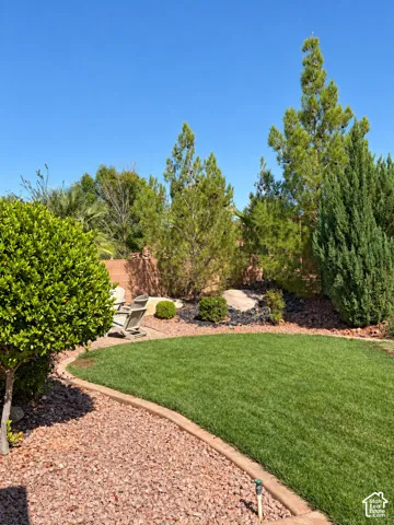 Manicured lawn with a concrete border, surrounded by red gravel and diverse shrubbery