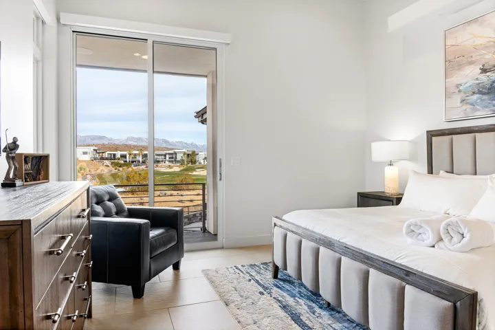 Sliding glass door leading to a balcony with metal railing, featuring a mountain and golf course landscape